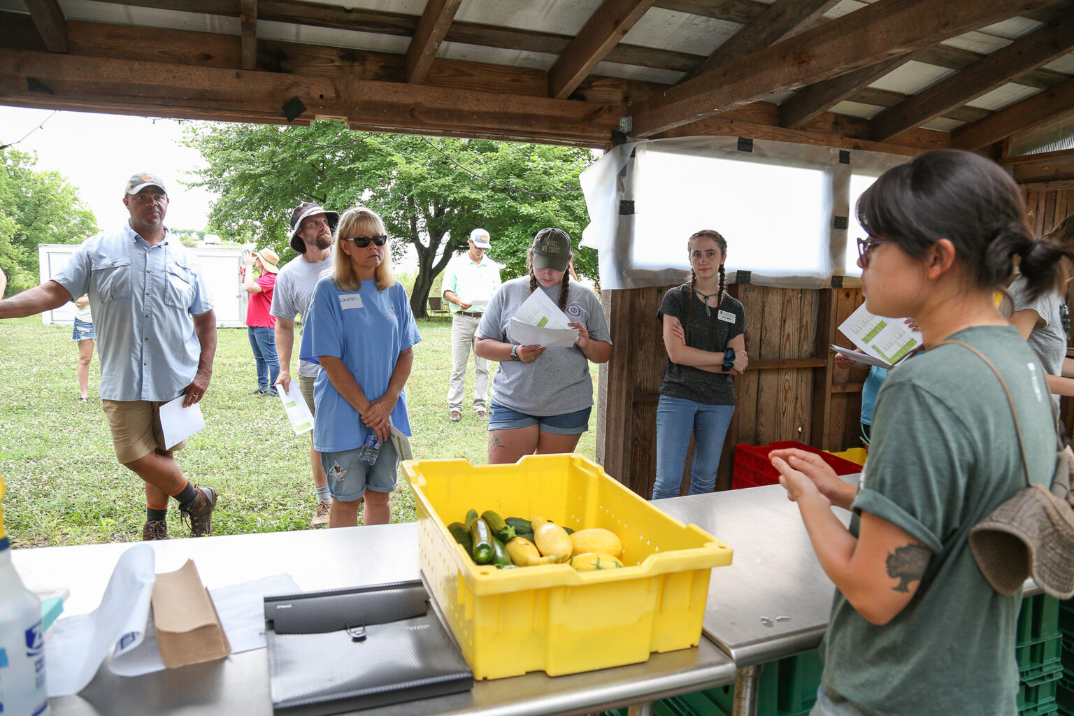 A Grow It Know It teacher instructs a group of several teachers outdoors.