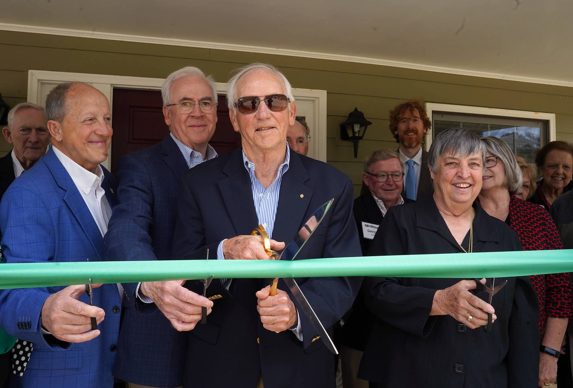 Thomas F. Rodgers smiles while surrounded by Georgia 4-H leaders and preparing to cut the green ribbon tied across the front of the administration building
