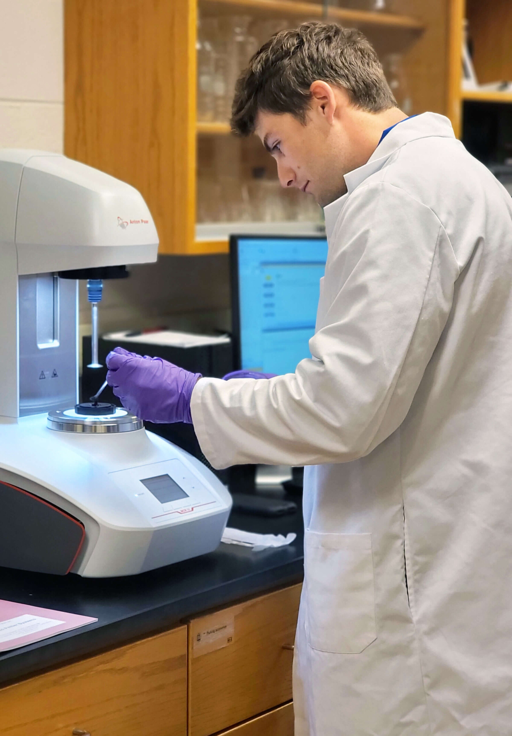 Wearing a white lab coat, Peter Chiarelli works in the Mis Solval Lab at UGA-Griffin