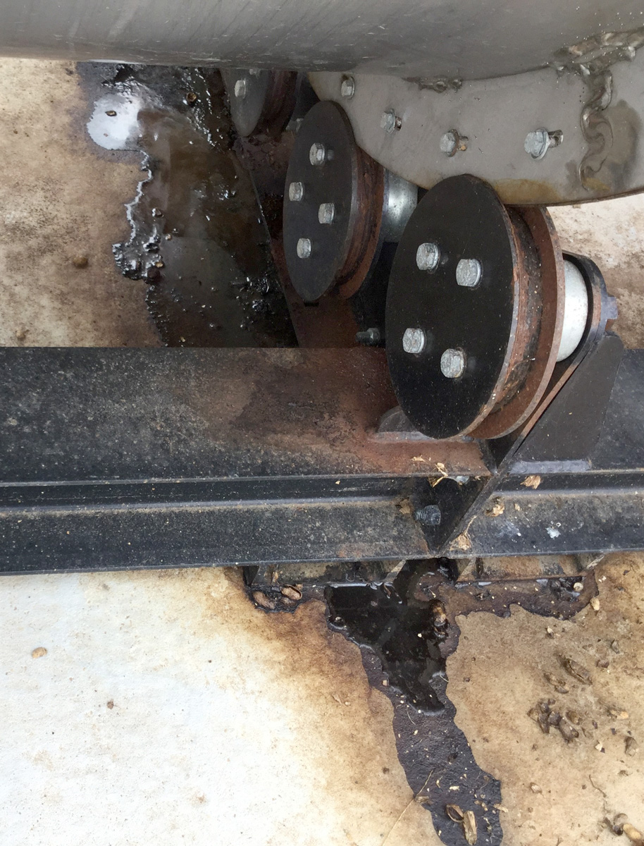 Leaking liquid is visible on the ground below the drum composter, indicating the material inside is too wet.