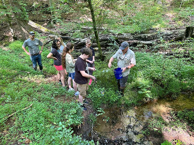 Warnell professor Kris Irwin (right) helps campers set leaf-litter traps to capture macroinvertebrates, small amphibians and other organisms during Natural Resources Exploration Camp at Rock Eagle 4-H Center.