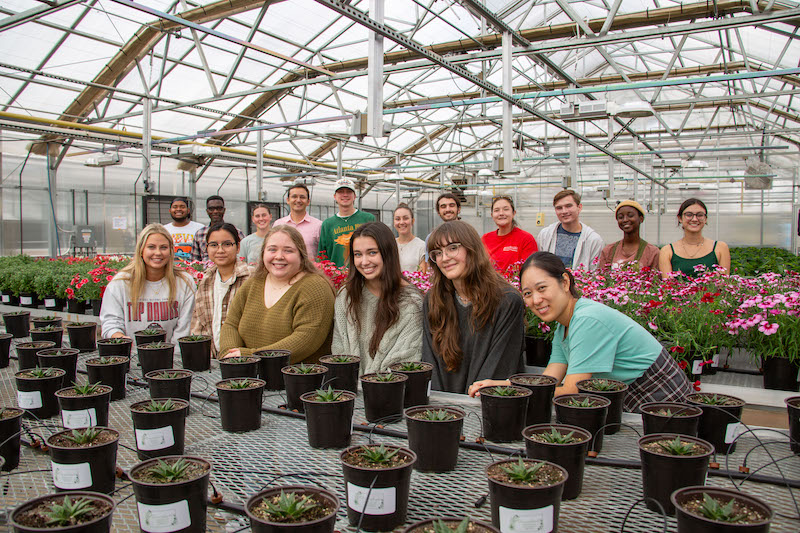 Students in the Greenhouse Management class pose among the hundreds of ornamental plants they cultivated for student-run sales.