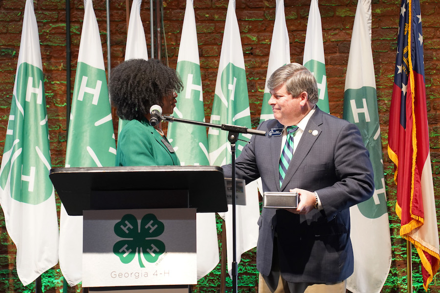 Georgia 4-H'er Naomi Jackson shakes hands with Sen. Larry Walker at a lectern at the Georgia Capitol.