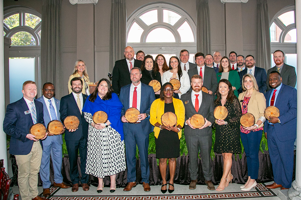 A large group of adults stands holding awards, smiling at the camera.