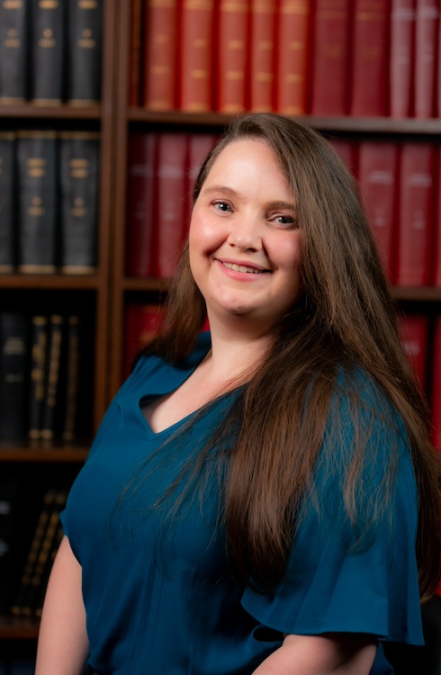 A headshot of Micaela Sinclair-Black in a library setting