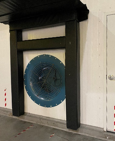 A cooling fan is installed in the wall of a cold room.