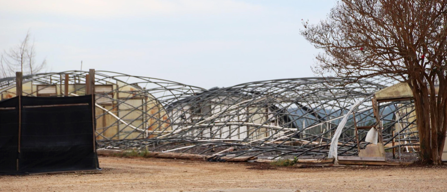 Hoop houses have had their coverings torn off and debris is seen on the ground surrounding them