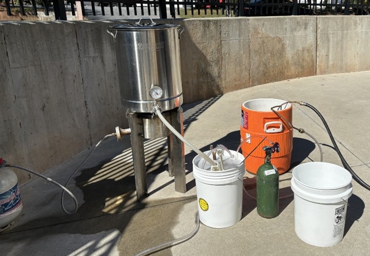 An arrangement of homebrew tools are set against a concrete wall.