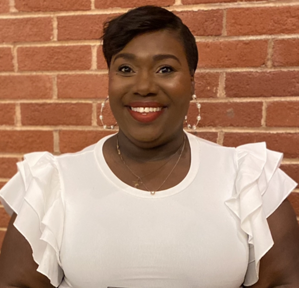 Wearing a white blouse, Ida Jackson poses for her professional headshot outdoors