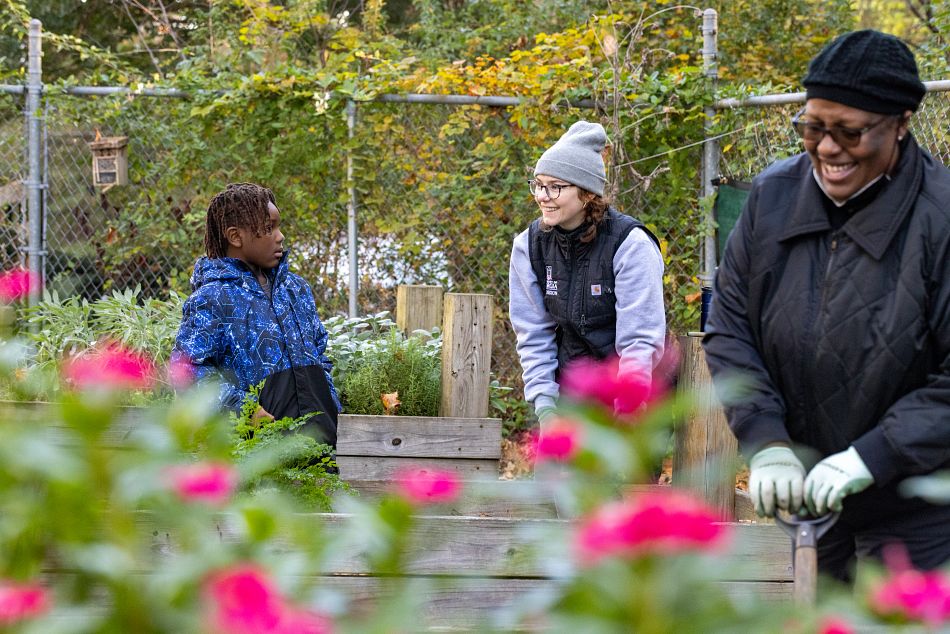 Local resident Maxwell Barton and Fulton County extension agent Gabrielle LaTora pull weeds from a planting bed during a community cleaning day at the North Fulton Community Garden in Atlanta, GA.