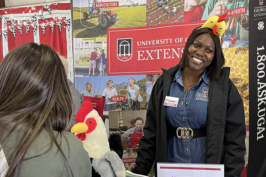 A graduate student engages with a man at a UGA Cooperative Extension booth, providing information to constituents.