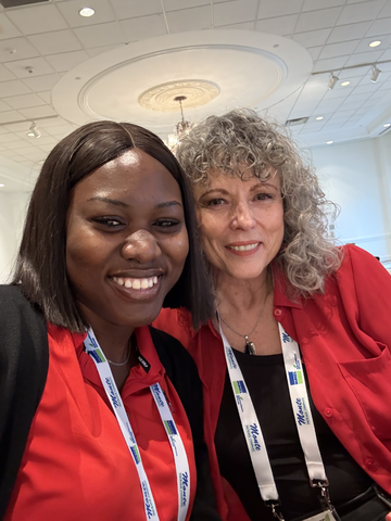 A UGA graduate student in a red shirt poses with a female faculty member with shoulder length curly salt and pepper hair.